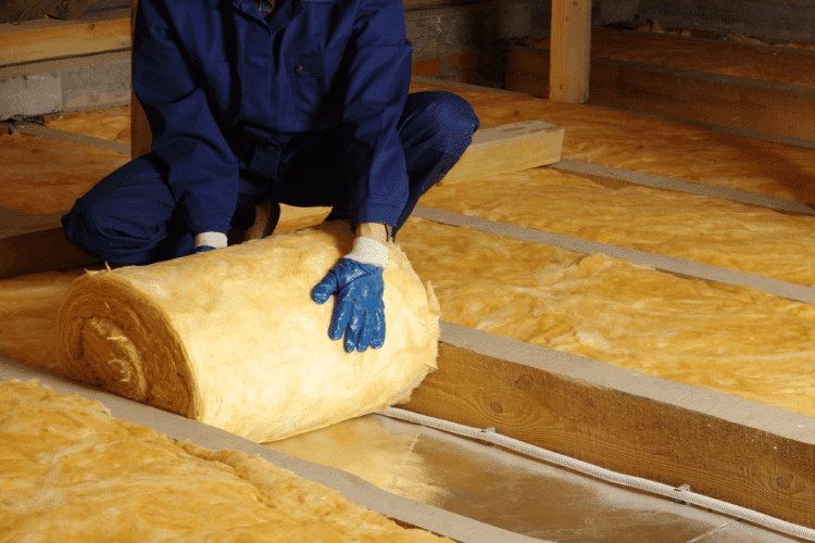 Een dakwerker isoleert een zolder met glaswol.