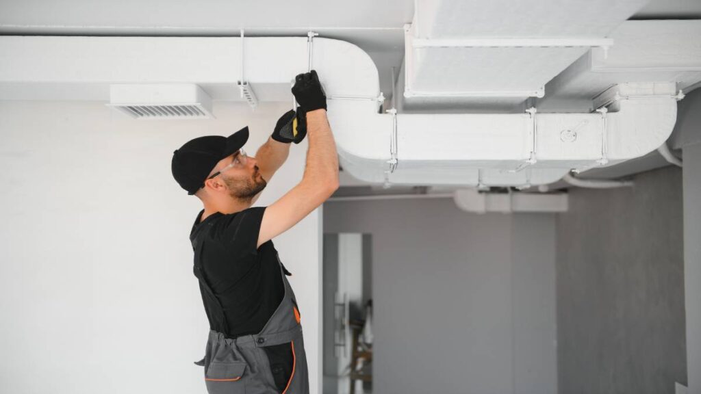 Een ventilatiespecialist is bezig met het installeren van een ventilatiesysteem in een huis.
