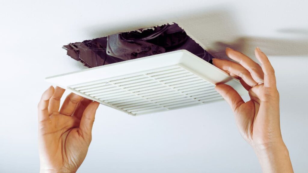 De badkamerspecialist monteert een badkamerventilator voor betere ventilatie.