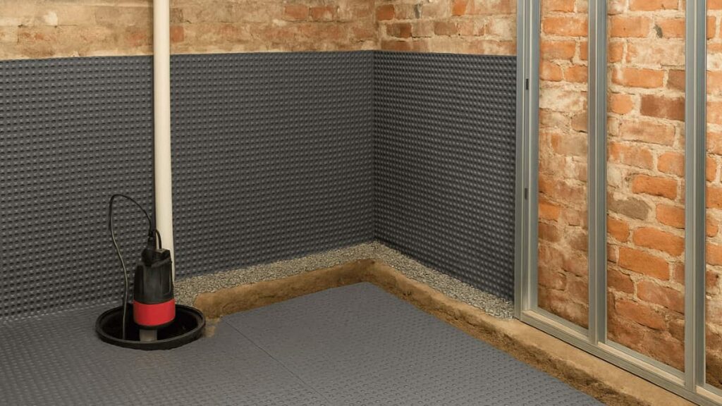 Een keldermuur bekleed met witte noppenfolie, voorzien van een drainagekanaal en een dompelpomp in een afvoerput voor waterafvoer.